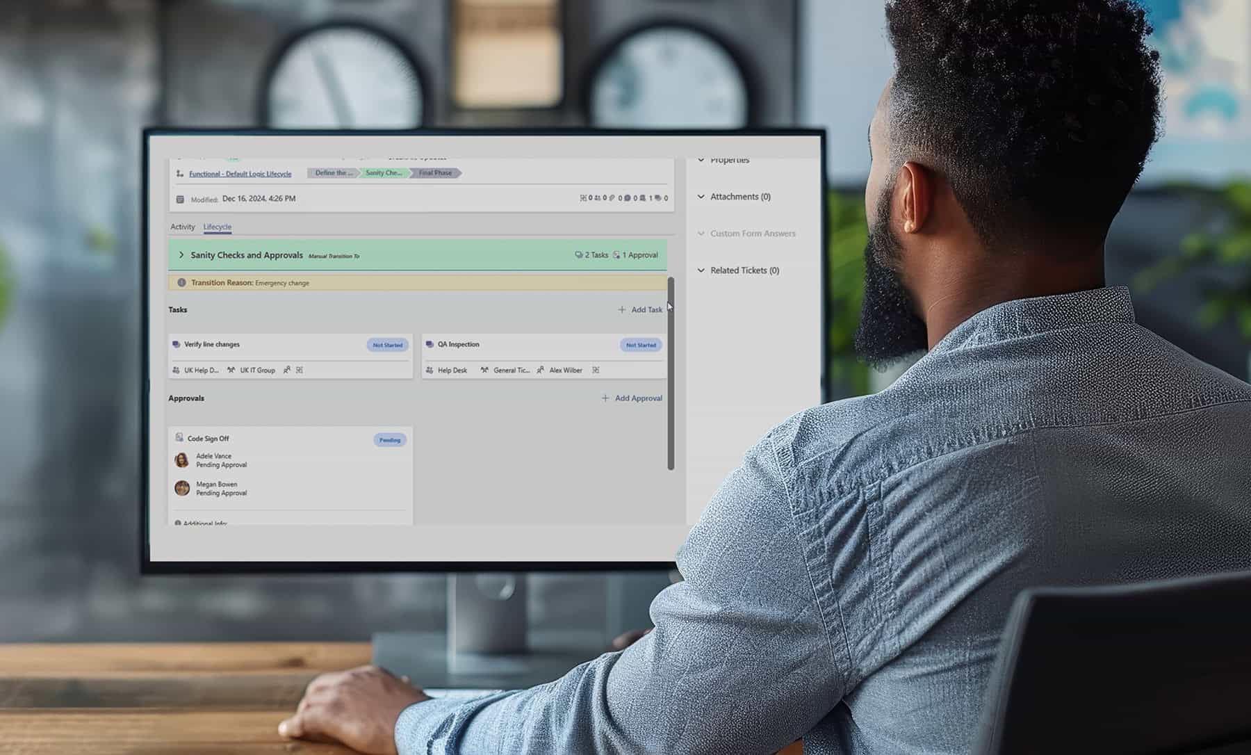 A man is sitting at a desk in front of a computer monitor with a lot of graphs